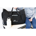 Marshmallow Axis Glass Chug Bottle - 21 Oz. shown next to a bag and a person