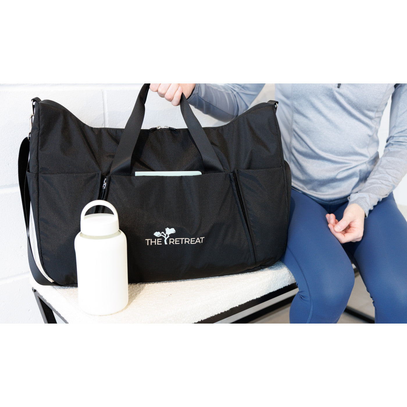Marshmallow Axis Glass Chug Bottle - 21 Oz. shown next to a bag and a person