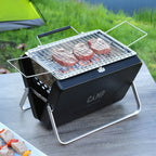 Portable grill with steaks on a camping table outdoors