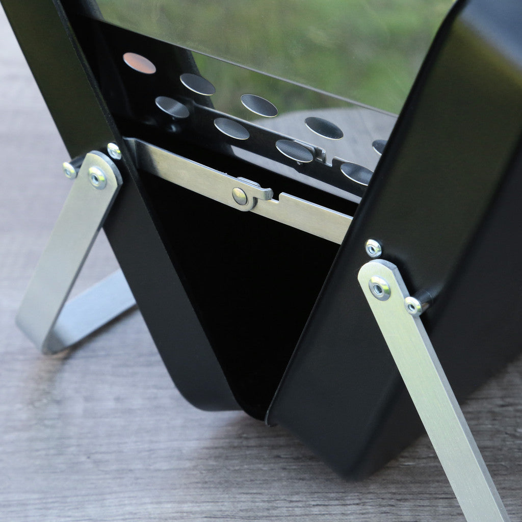 Black metal stand with adjustable legs on a gray surface