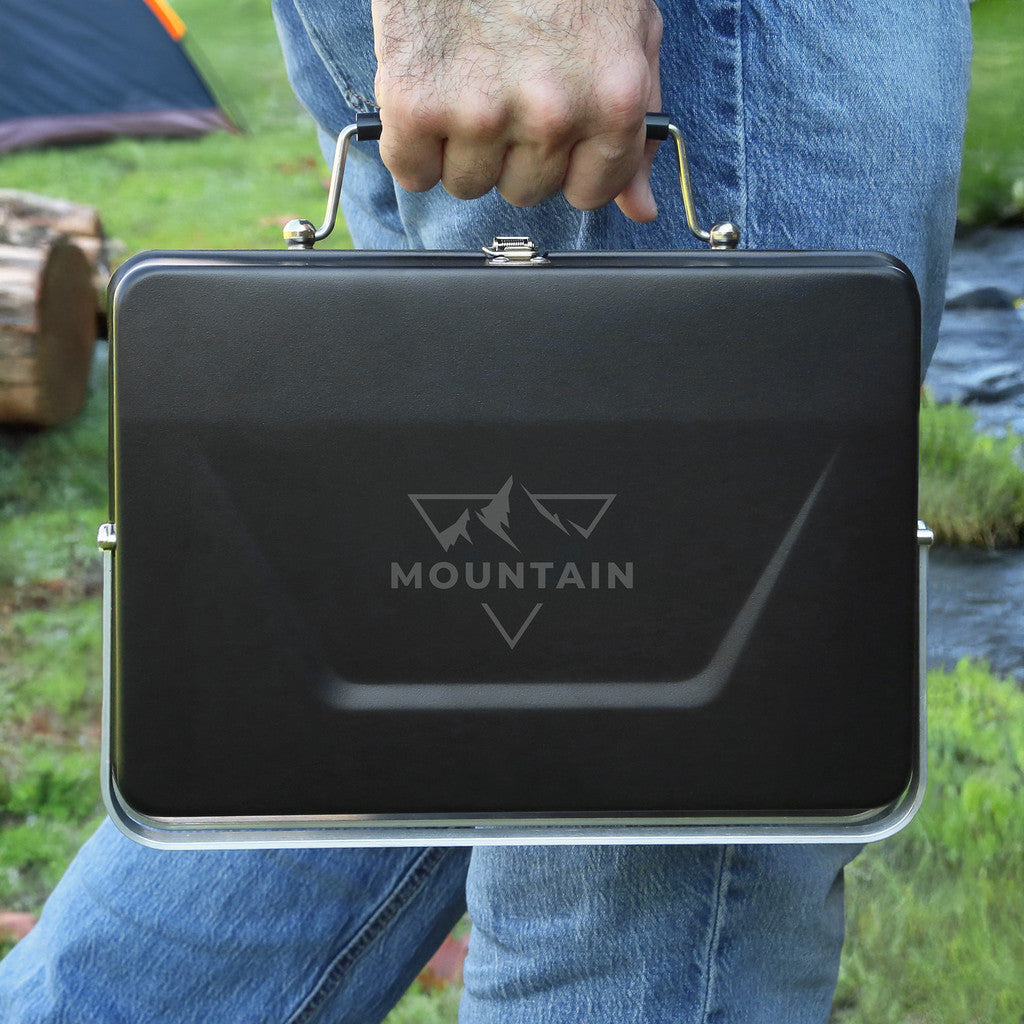 Person holding a black briefcase with 'Mountain' branding outdoors.