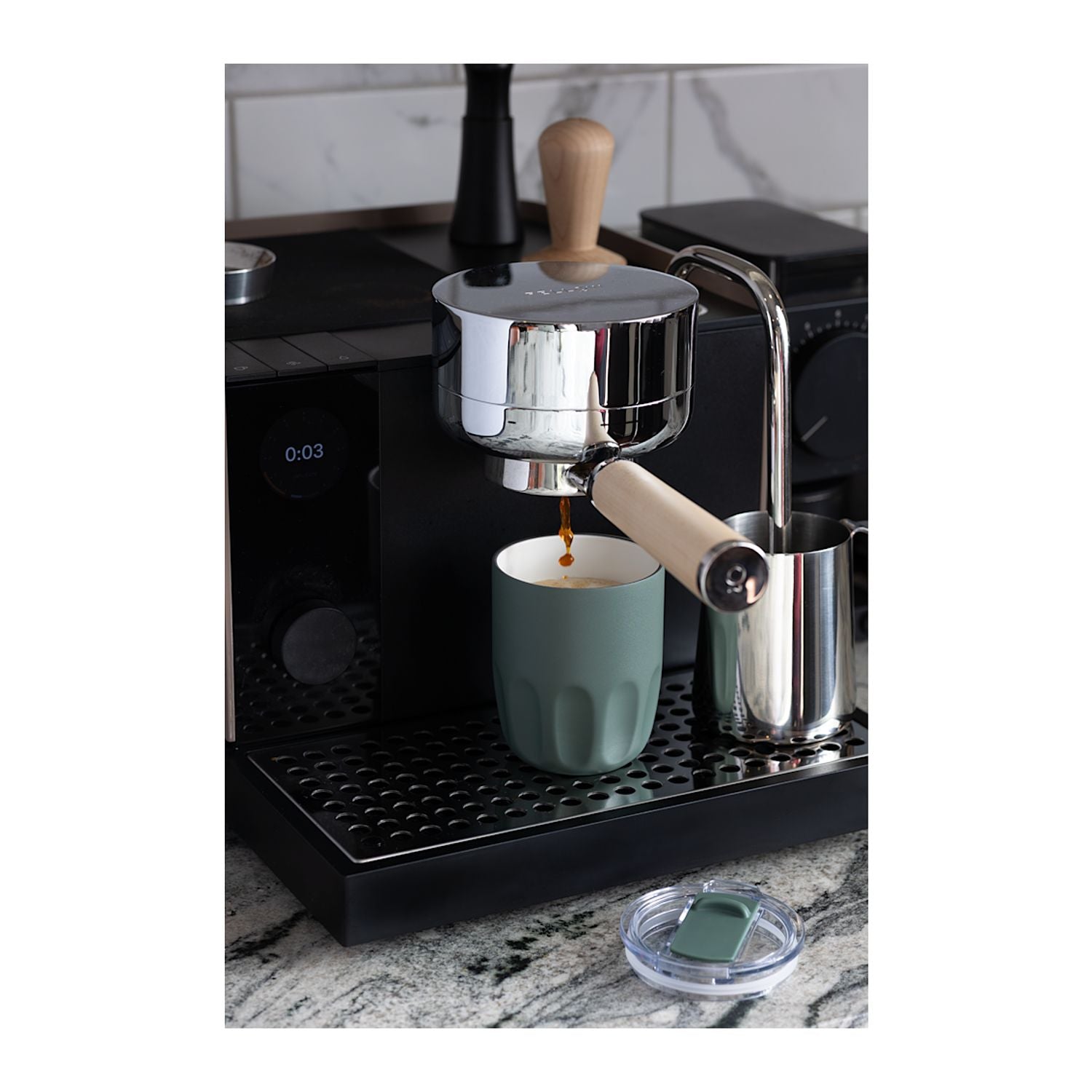A black espresso machine with a stainless steel portafilter and wooden handle dispensing coffee into an Olla 10 oz Vacuum Coffee Cup with Ceramic Liner