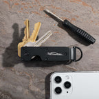 Key organizer with keys, screwdriver, and smartphone on a textured surface