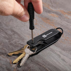 Multi-tool keychain with screwdriver and keys on a textured surface