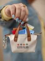 Natural Mini Fontaine Tote Charm with a custom logo shown in someone's hands