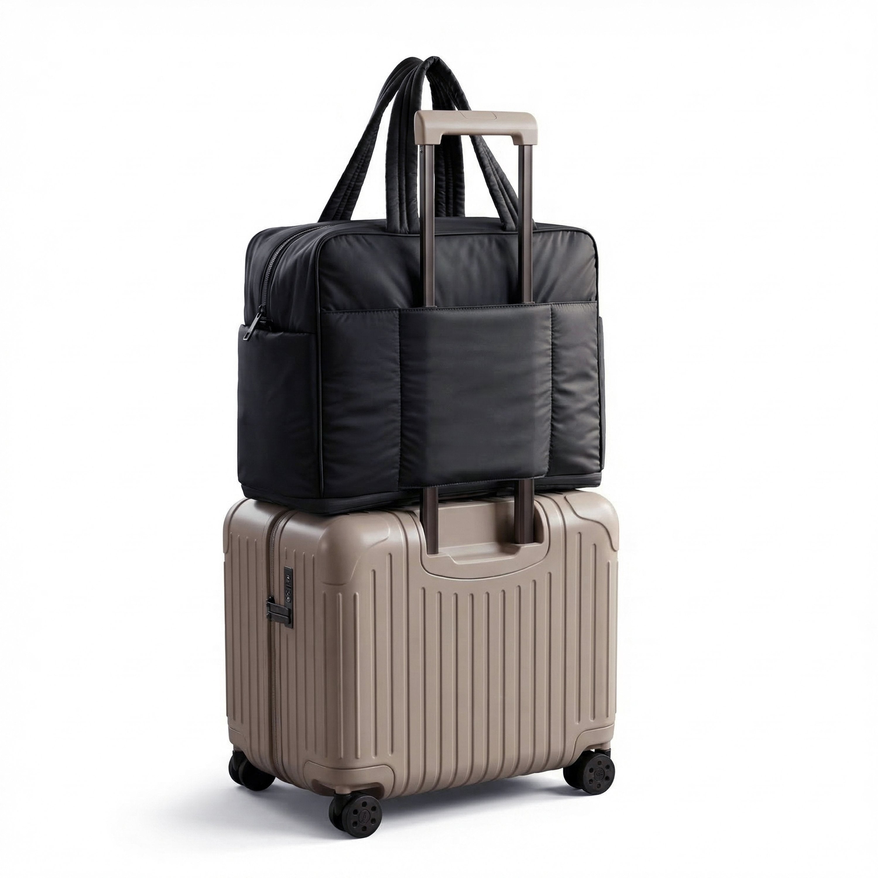 Black travel bag on top of a beige suitcase on a white background