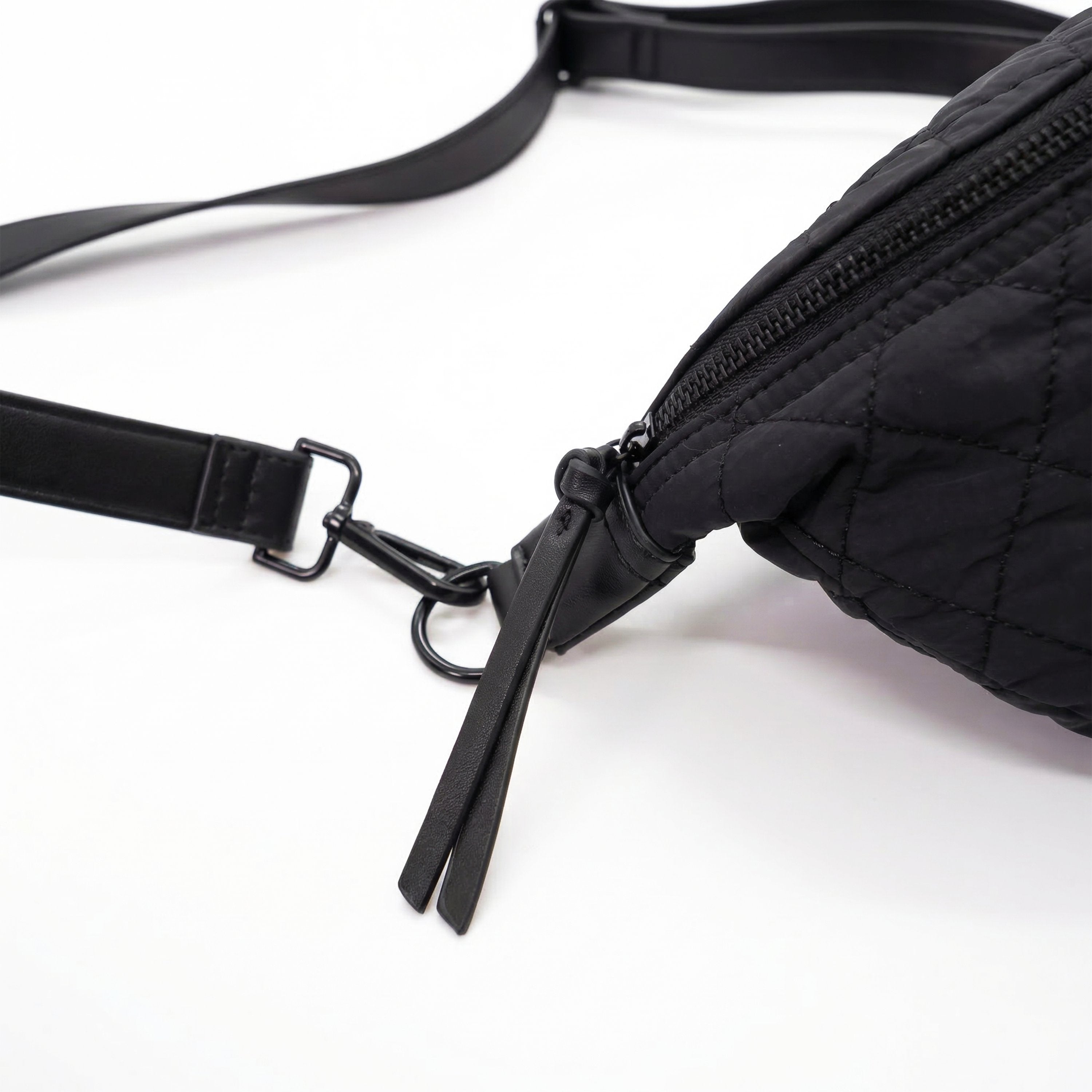 Black quilted fanny pack with a strap on a white background