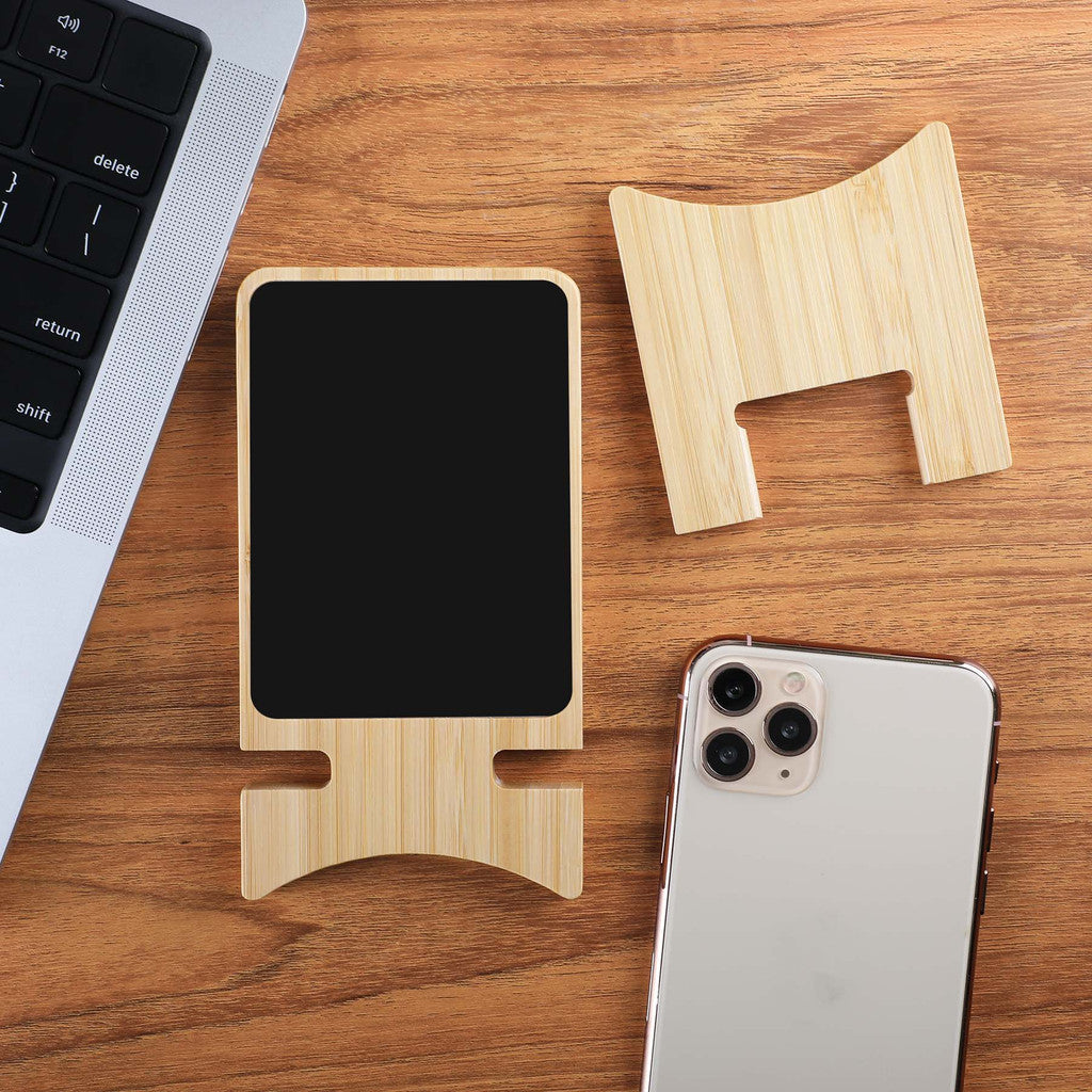 Wooden phone stand on a wooden desk with a smartphone and laptop.