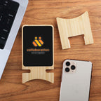Wooden phone stand with custom logo displayed on a wooden desk with phone and laptop.