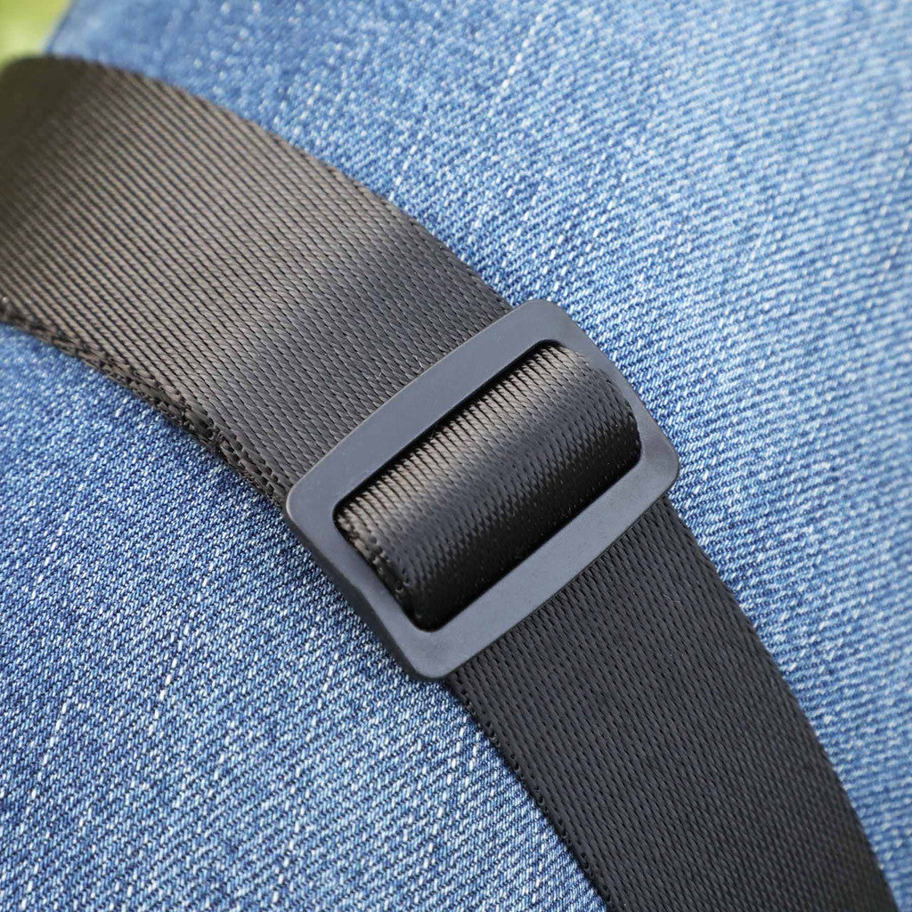 Close-up of a black adjustable web belt with a matte black plastic buckle, worn over blue denim fabric.