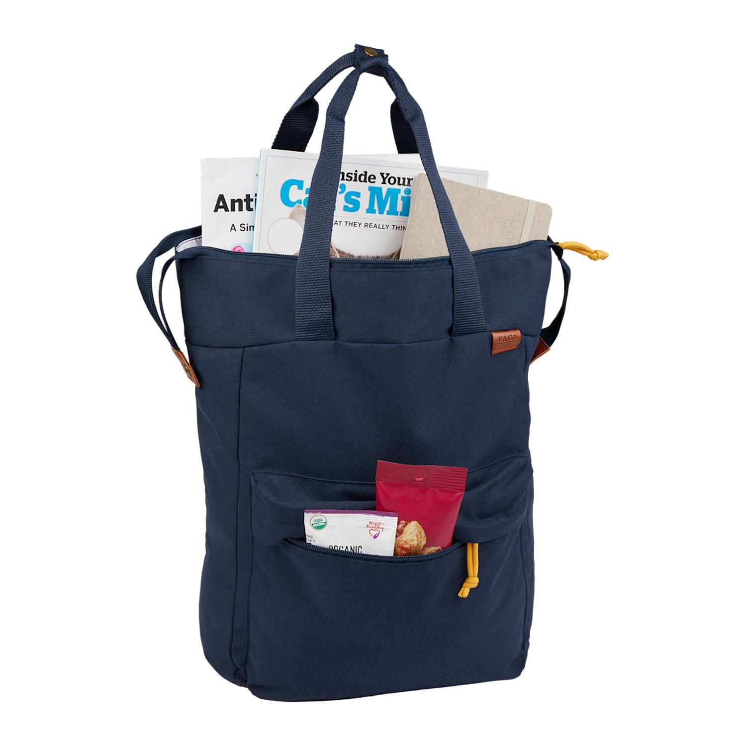 Navy blue tote bag with handles and a front pocket, filled with magazines and items. Contents not included