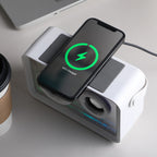 Smartphone charging on a multi-device charging station with a laptop and coffee cup in the background.