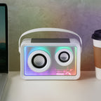 Portable speaker with colorful LED lights on a desk next to a laptop and coffee cup.
