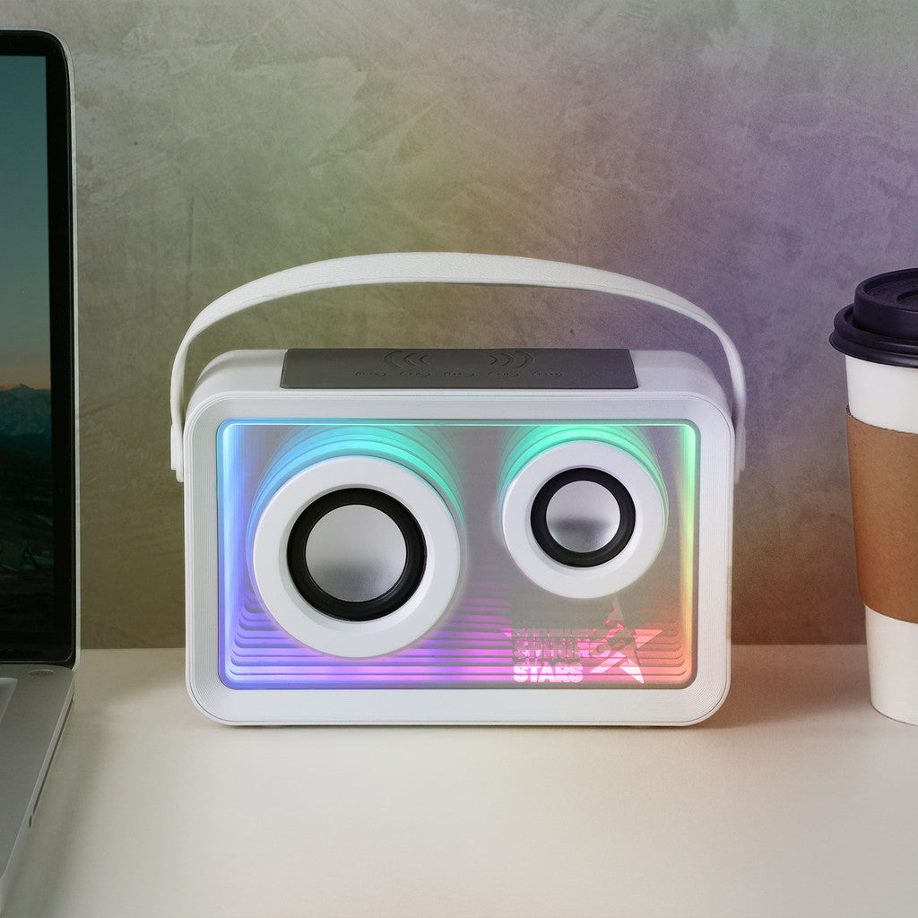 Portable speaker with colorful LED lights on a desk next to a laptop and coffee cup.