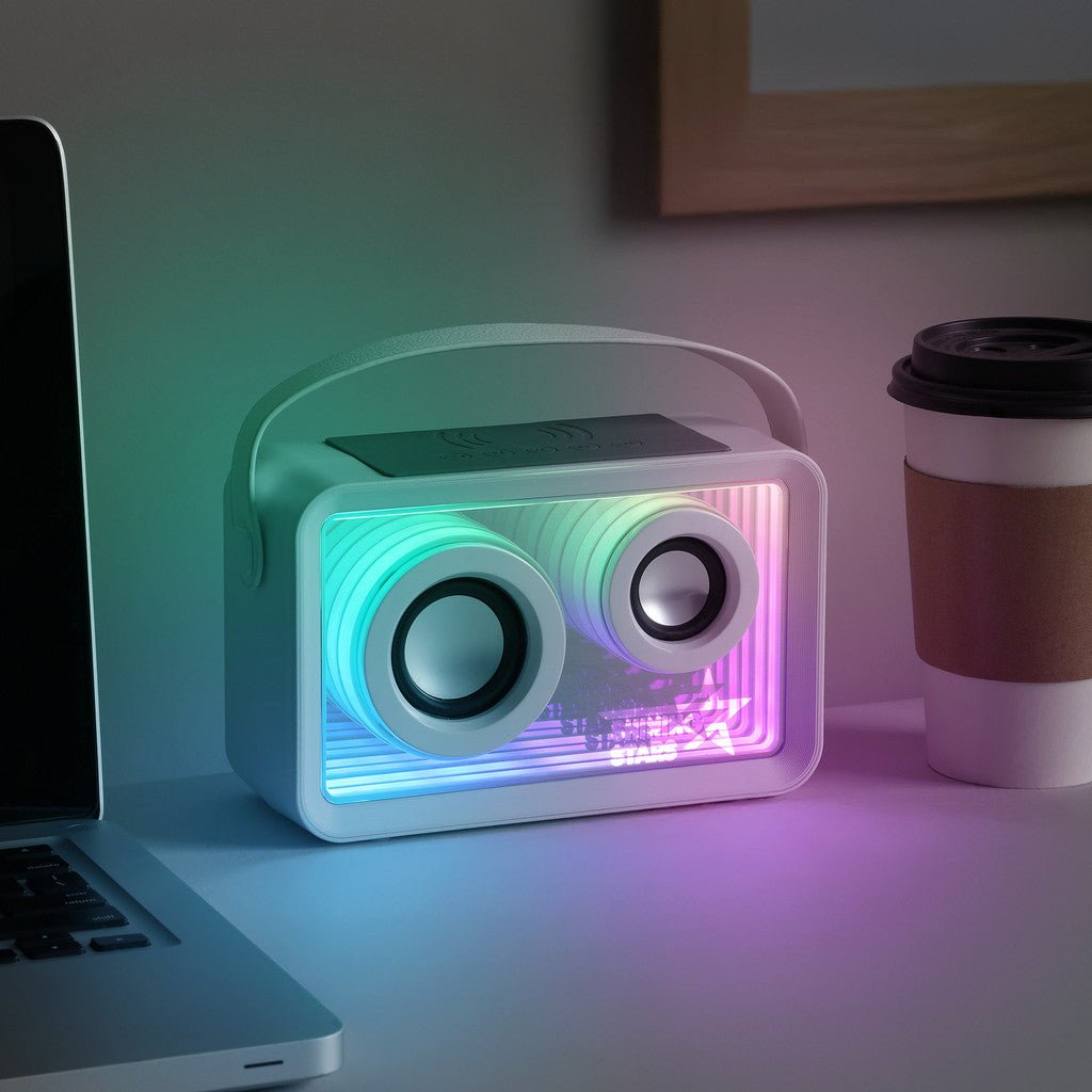 Colorful portable speaker on a desk with a laptop and coffee cup in the background