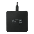 A black square wireless charging pad with a USB cable attached at the top, featuring white printed text and an FCC logo on the front, set against a plain white background.