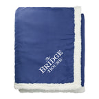 Blue blanket with white trim and 'The Bridge House' logo on a white background