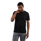 Man wearing a black t-shirt and gray pants against a plain background